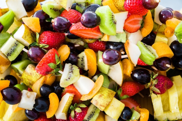 Colorful mixed fruit salad served on barbecue sticks Selective focus Top view