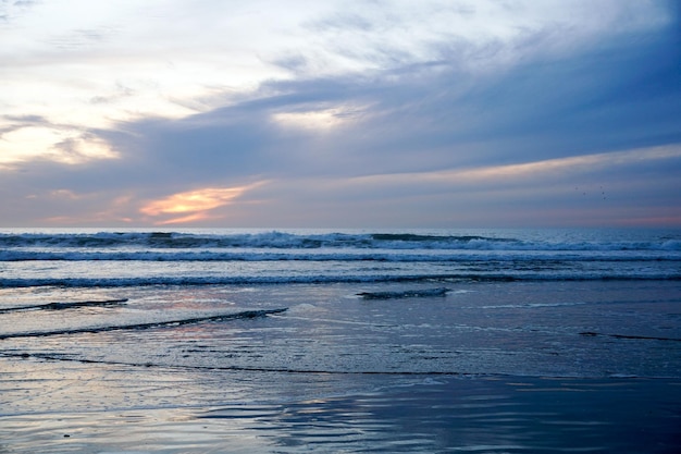 Colorful orange ocean beach sunset with deep clouded sky. Beautiful cloud over the sea during sunset