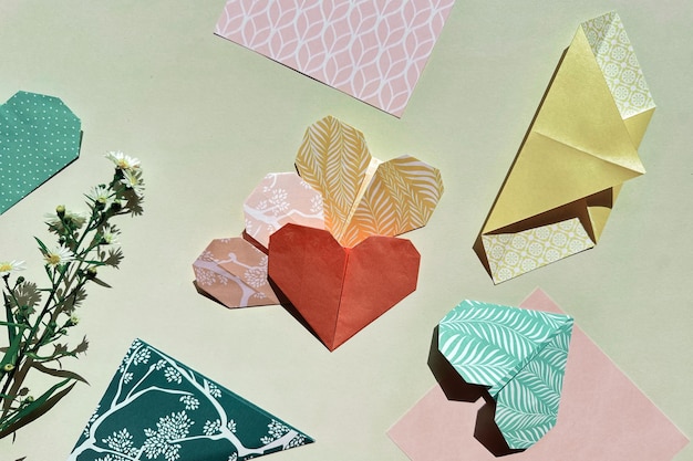 Photo colorful origami hearts and patterned paper set against a pastel background accompanied by delicate