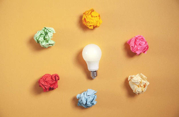 Colorful paper balls and light bulb on yellow background.