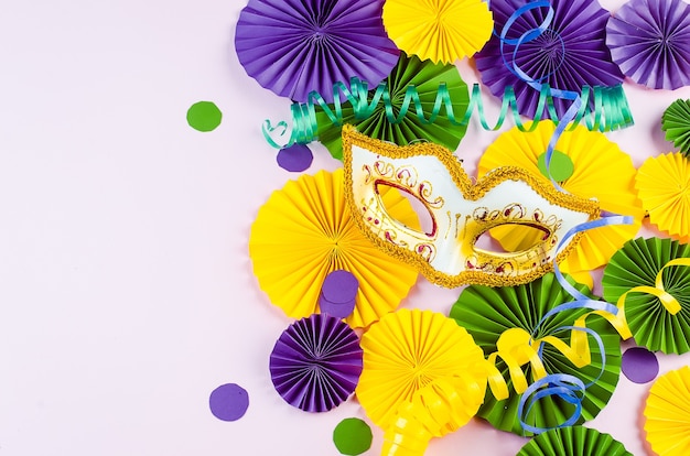 Colorful paper confetti, carnivale mask and colored serpentine on a yellow background