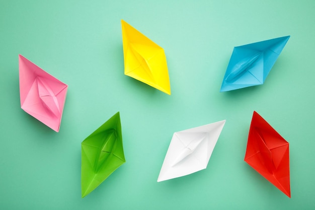 Colorful paper ships on mint background Leadership and Business competition concepts