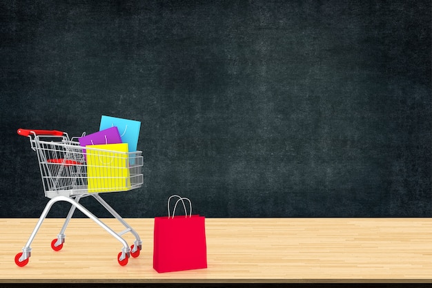 Colorful paper shopping bags in trolley on wood table 