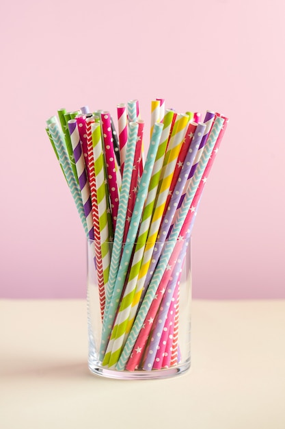 Colorful paper tubes for drinks in a glass on colored surfaces