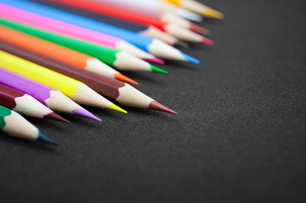 Colorful pencils on black background with copy space.