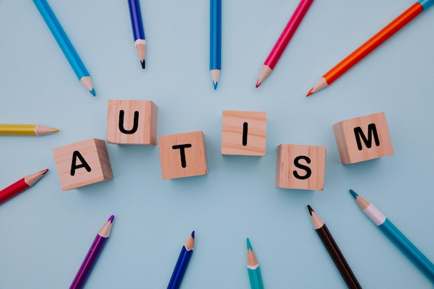 Colorful pencils and blocks with AUTISM word on blue background Top view World autism awareness day concept