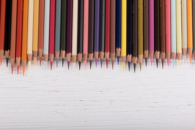 Colorful pencils lay on white wooden floor.