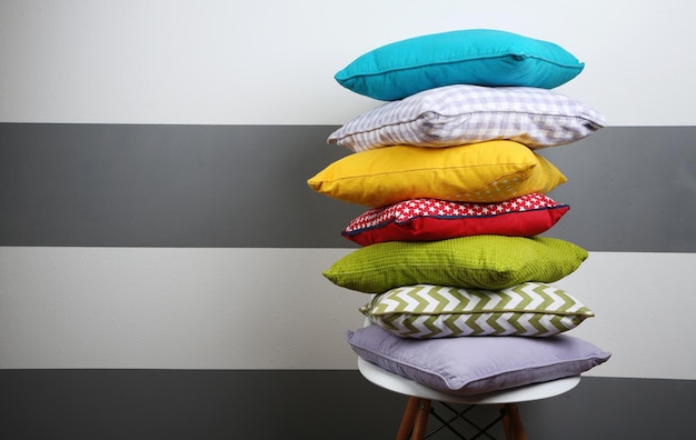 Colorful pillows on chair on striped grey wall background