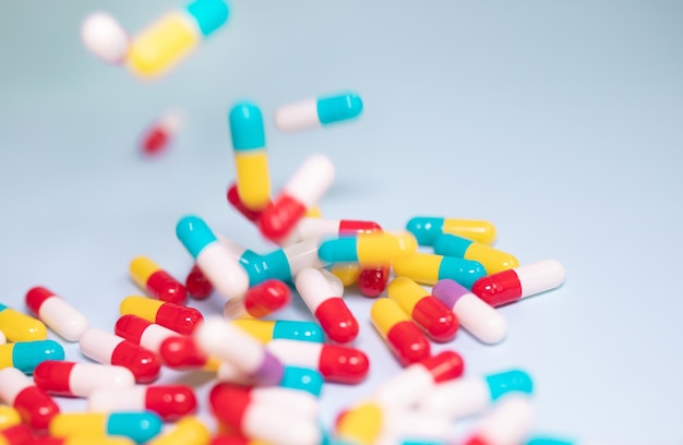 Colorful pills and capsules on blue background. Minimal medical concept. Pharmaceutical, Medicine.