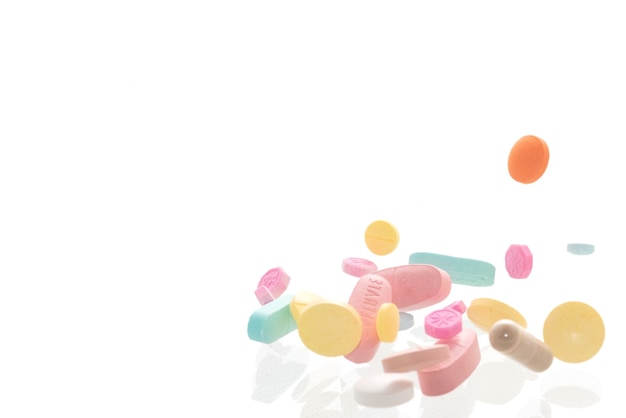 Colorful pills of various shapes on white background