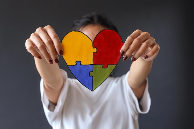 colorful puzzle heart shape covering face of young girl. World Autism Awareness Day.