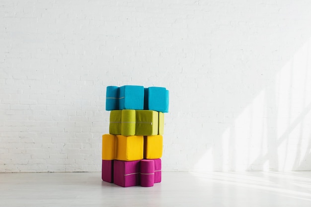 Colorful puzzle shape poufs near white brick wall at home