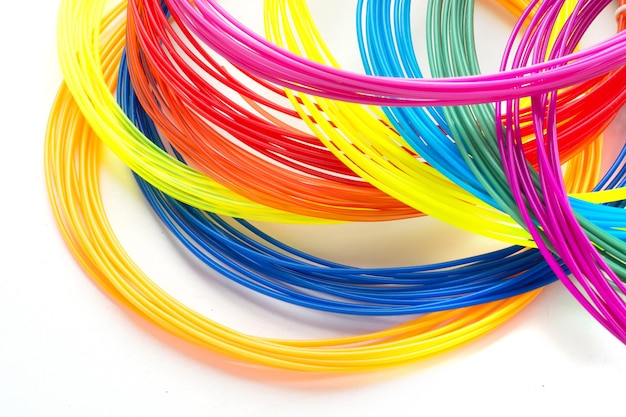 Colorful rainbow plastic filaments for 3D pen laying on white background New toy for child