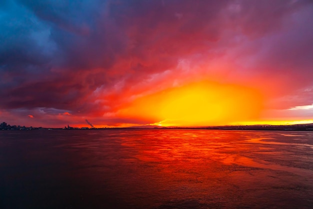 Colorful red and blue sunset in the sea bay at dusk and the city in the distance