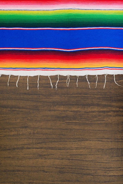 Colorful serape on wooden table Typical colorful fabric from Mexico Texture background