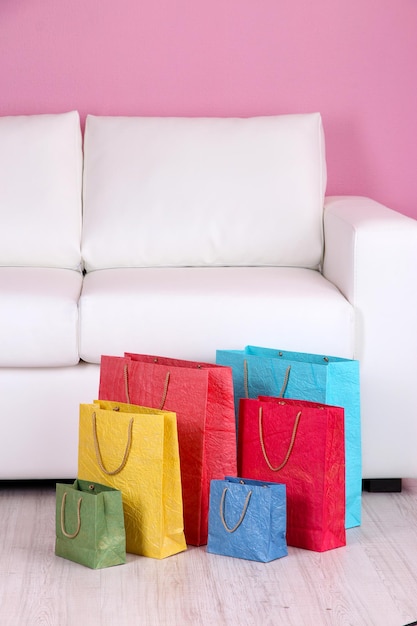 Colorful shopping bags on sofa on color wall background