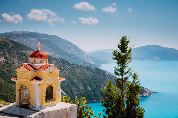 Colorful shrine Proskinitari on pedestal Amazing sea view to Greece coastline in the background