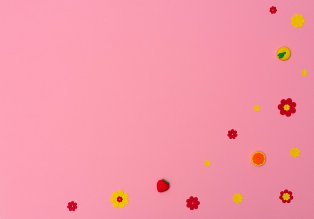 Colorful small erasers with fruits and flowers shapes on pink background with copy space