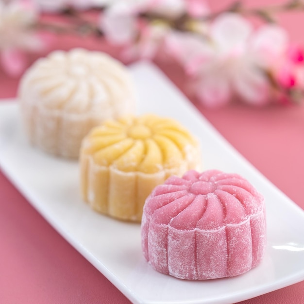 Colorful snow skin moon cake sweet snowy mooncake traditional savory dessert for MidAutumn Festival on pastel pale pink background close up lifestyle