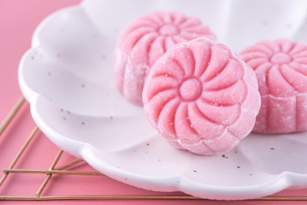 Colorful snow skin moon cake sweet snowy mooncake traditional savory dessert for MidAutumn Festival on pastel pale pink background close up lifestyle