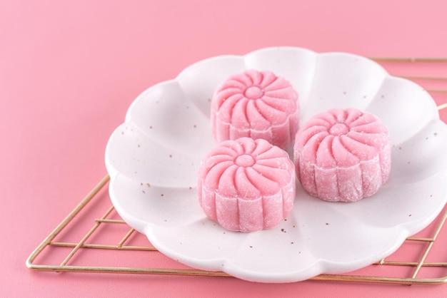 Colorful snow skin moon cake sweet snowy mooncake traditional savory dessert for MidAutumn Festival on pastel pale pink background close up lifestyle