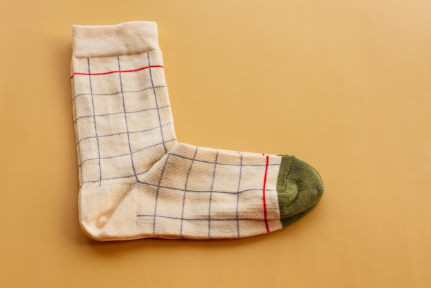 Colorful sock on beige surface, top view. Knitted socks