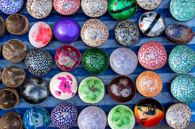 Colorful souvenir bowls for tourists at street market in Thailand. Bowls that make from coconut shell, close up, top view