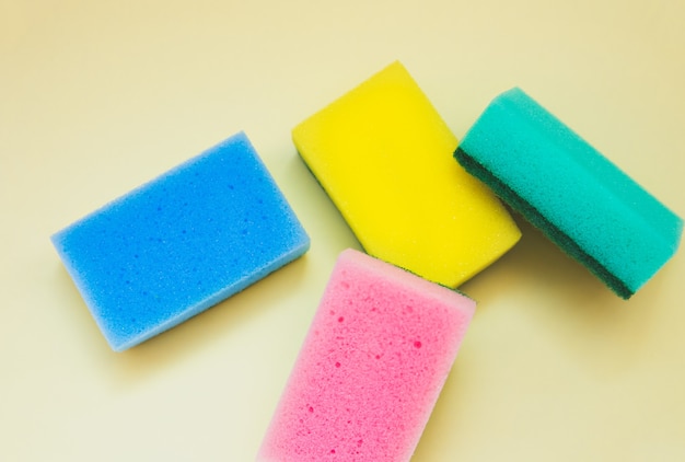 Colorful sponges for washing dishes on yellow background. Artificial fiber not eco-friendly tool. Things for kitchen.