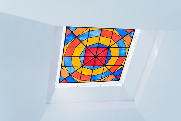 Colorful square stained glass window in a white painted ceiling View from inside