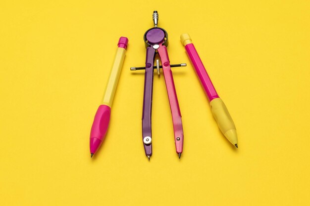 Photo colorful stationery trio compass yellow and pink pencils on vibrant yellow background