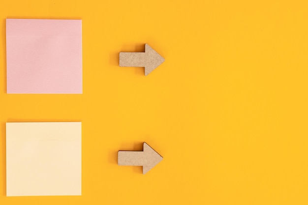 Colorful sticky notes and different wooden arrows on yellow background