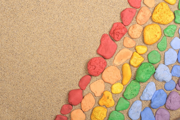 Colorful stones laid out on the sand with copy space