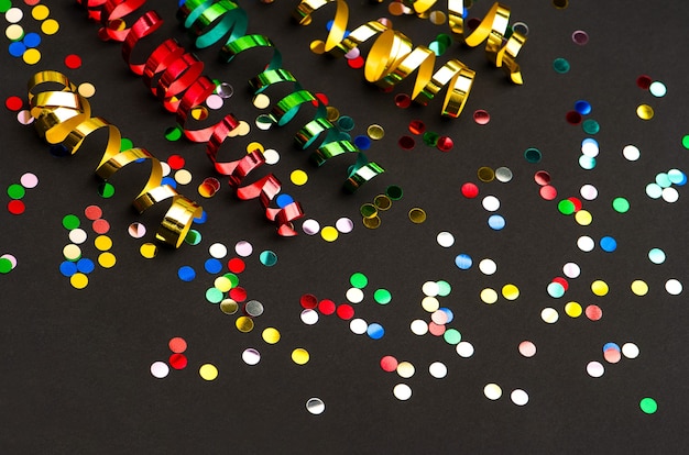 Colorful streamer and confetti on black paper background. party decoration