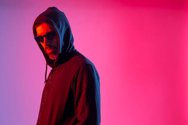 Colorful studio portrait of a bearded man with sunglasses against red and blue background.