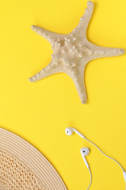 Colorful summer background starfish hat and headphones on a yellow background