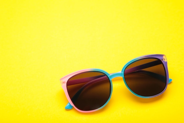 Colorful sunglasses on yellow background Top view