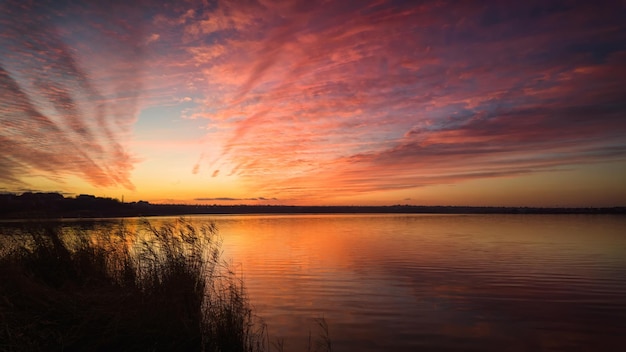 Colorful sunset on the river with reflections of clouds in the water