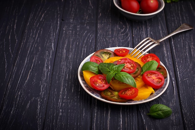 Photo colorful tomatoes salad in black background