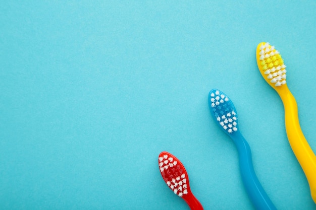 Colorful toothbrushes on blue background with copy space