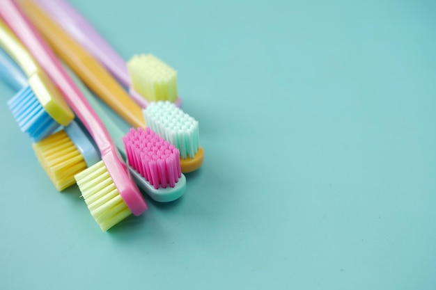 colorful toothbrushes on a light green background with copy space