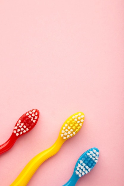 Colorful toothbrushes on pink background Top view