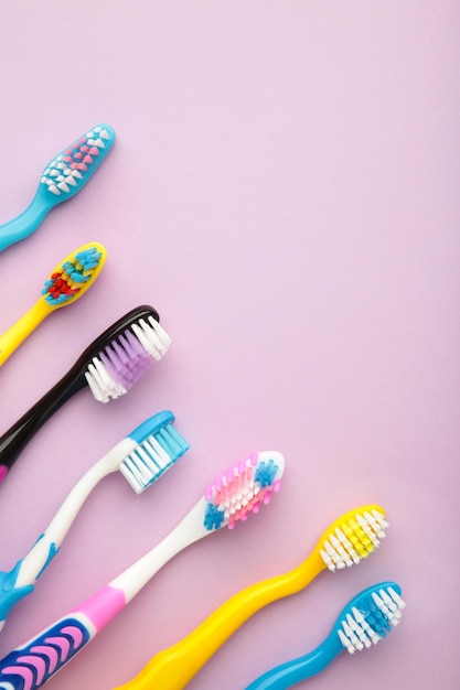 Colorful toothbrushes on purple background Vertical photo