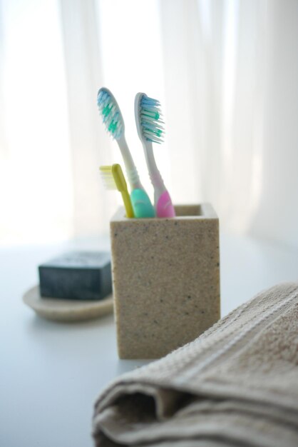 Colorful toothbrushes in white mug against a wall