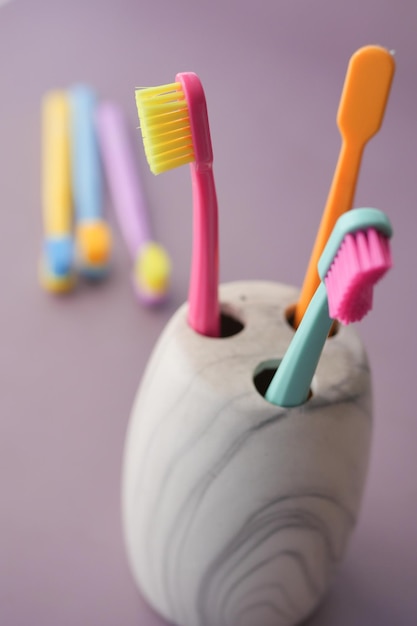 Colorful toothbrushes in white mug against a wall