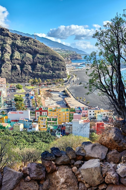 Colorful town houses or holiday resort accommodation near the seaside in a beautiful tourism destination La Palma Spain An ocean coast with black beach sand on Puerto de Tazacorte beach from above