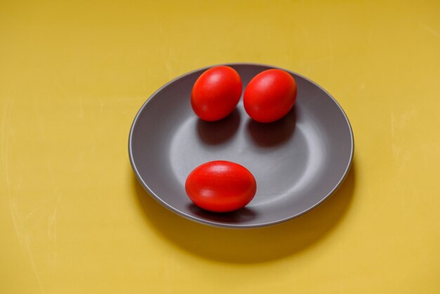 Colorful traditional painted Easter eggs. Red eggs, yellow background. Three eggs in a gray plate on a yellow background. Colors 2021