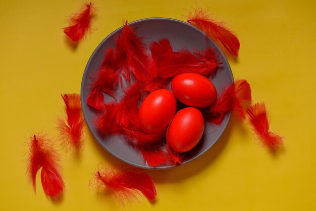 Colorful traditional painted Easter eggs. Red eggs, yellow background. Three eggs in a gray plate