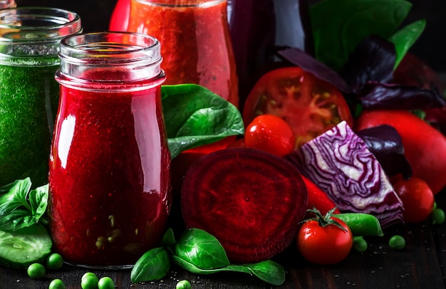 Colorful vegetable juices and smoothies from tomato carrot pepper cabbage spinach beetroot in bottles on kitchen table vegan food and drink selective focus