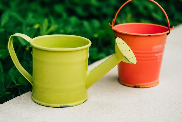 Colorful watering cans and buckets for plants in garden