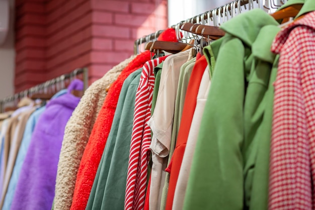 Colorful women's dresses, jackets, trousers and other clothes on hangers in a retail store.